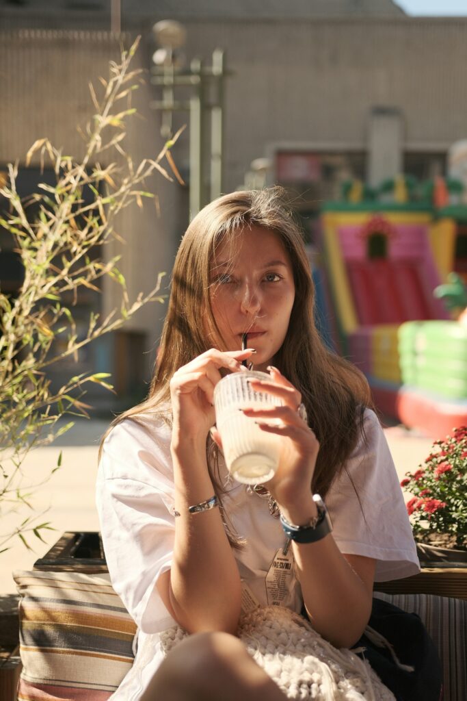 A smiling model drinking a green smoothie—highlighting the connection between internal wellness and skin health.